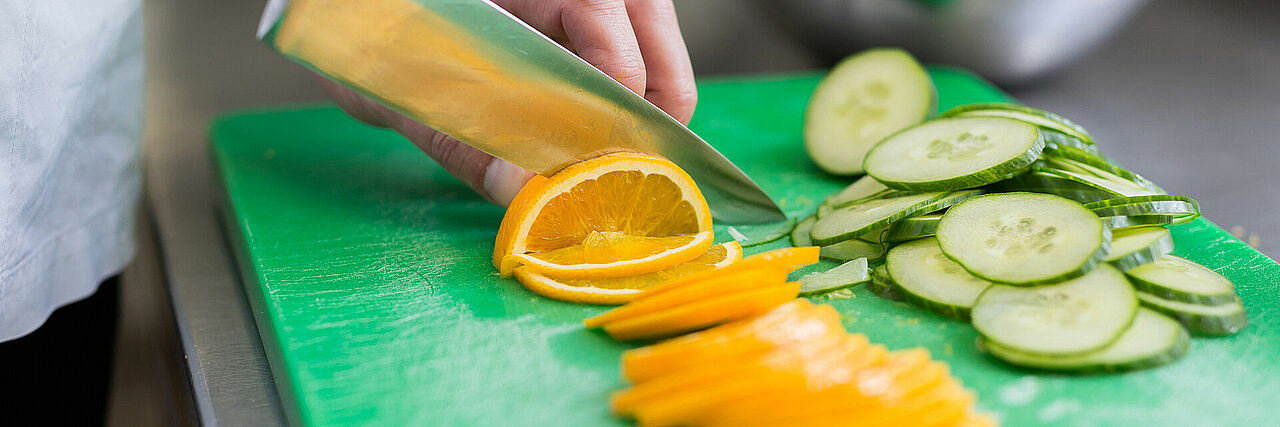 1920_Ernährung4.jpg Dekofoto: Messer schneidet Orangen, daneben Gurkenscheiben