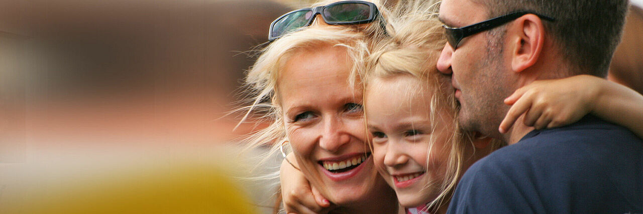 Gesicher einer Familie bestehend aus Mutter, Vater und Kind