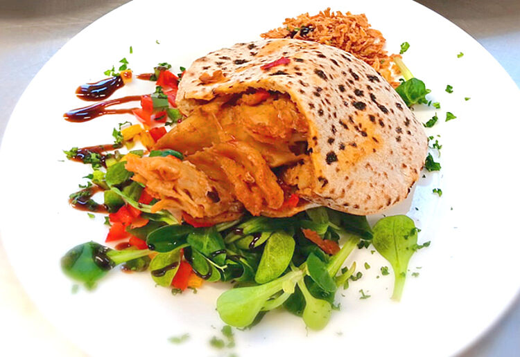Gesundes Mittagessen - Teller mit Fladenbrot auf Gemüsebett